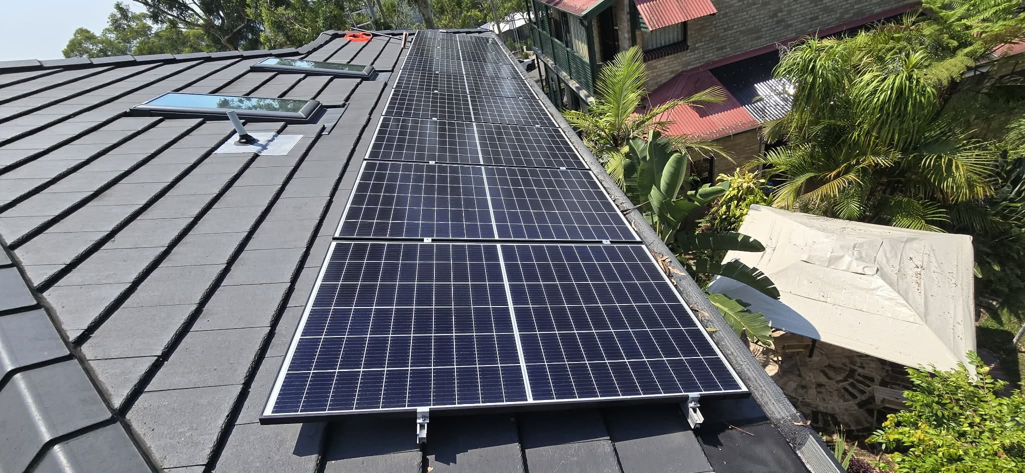 Row of freshly cleaned solar panels running along a dark tiled roof